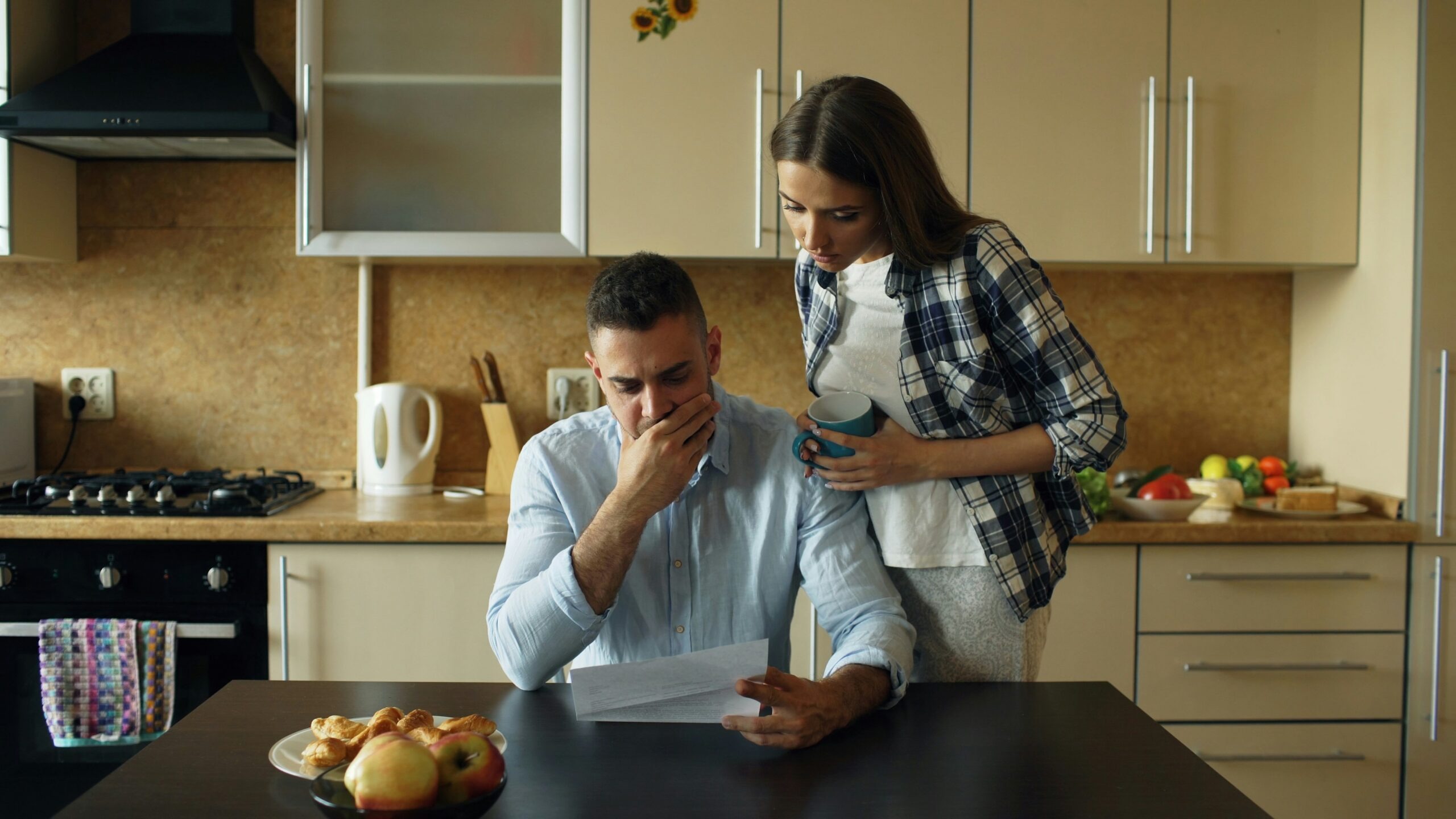Couple looking stressed over bills at kitchen table