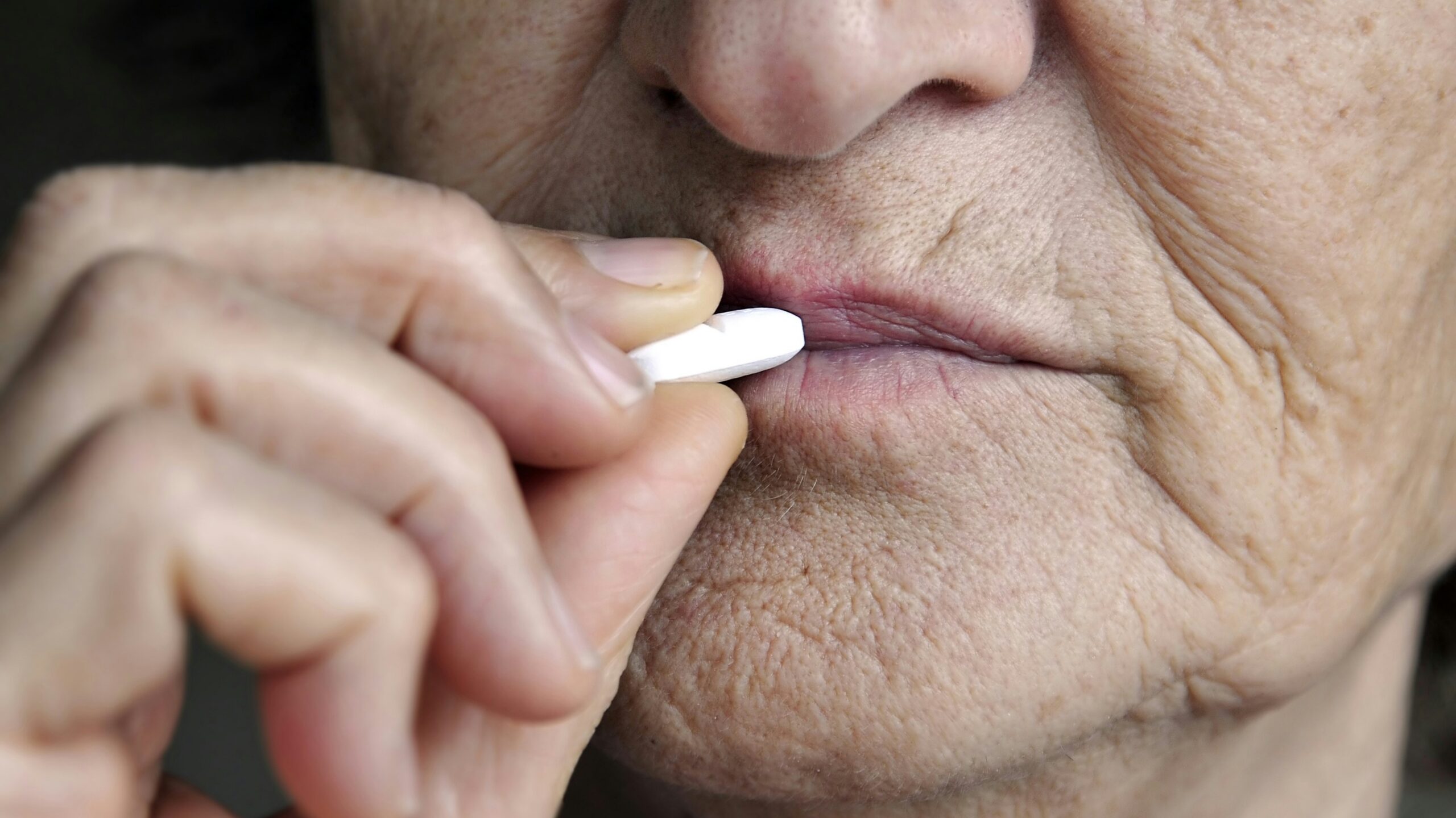 Elderly woman taking a white pill