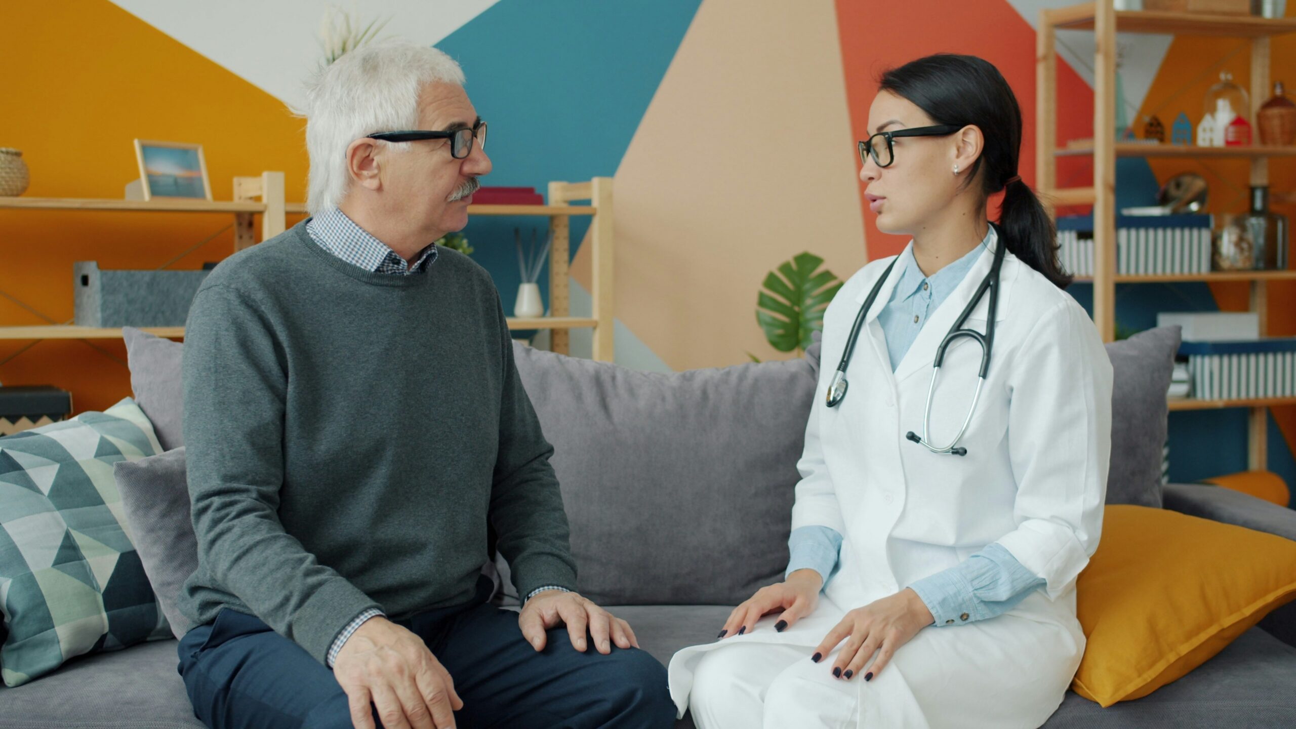 Doctor talks with an elderly patient on a couch