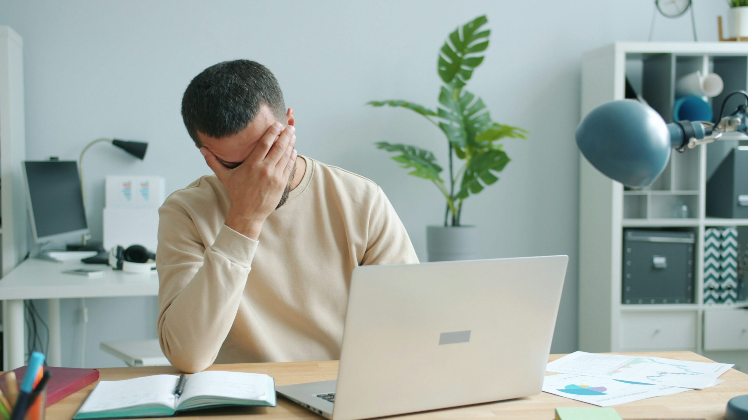 Man rubbing his face in front of laptop