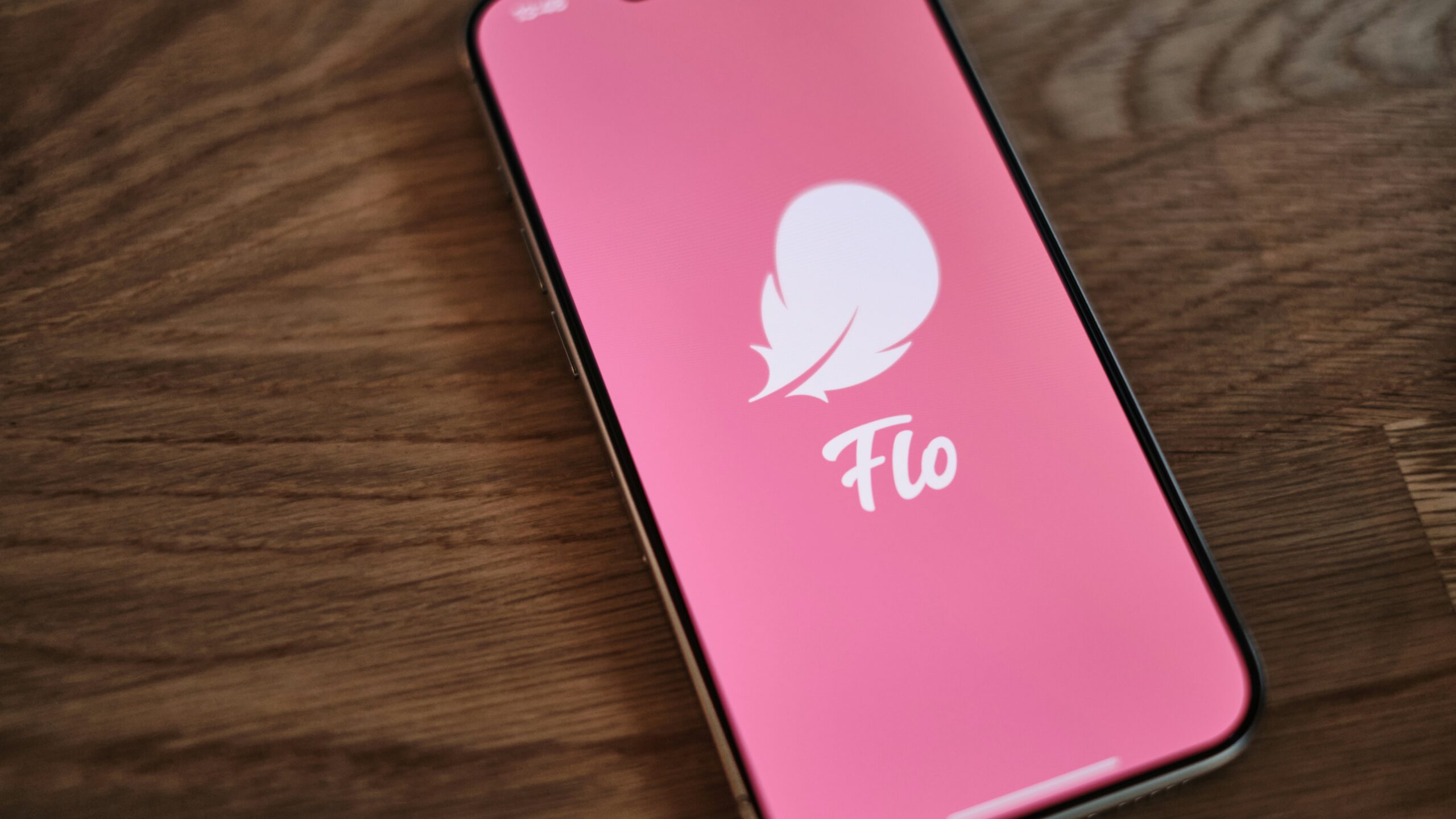 A pink phone sitting on top of a wooden table