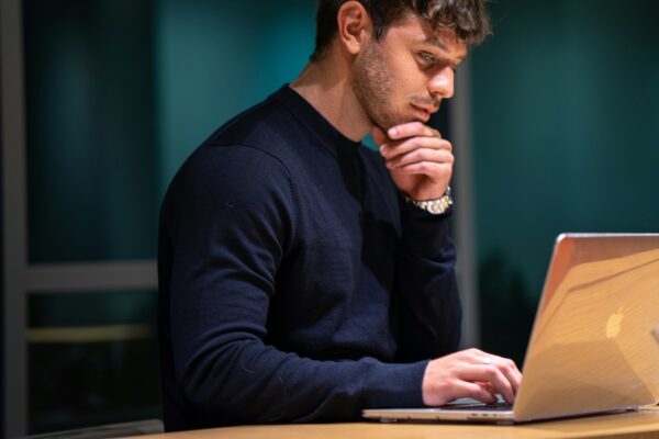 man in black long sleeve shirt sitting in front of macbook