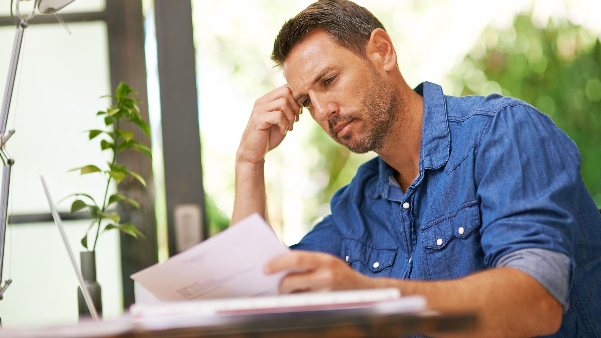Stress documents and man in home for finance budget financial review and mortgage payment Thinking reading and frustrated person with paperwork for insurance investment and bills for debt