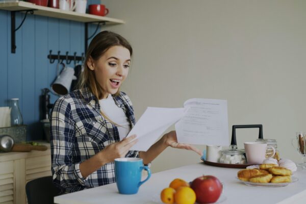 Woman with surprised expression reading documents at table