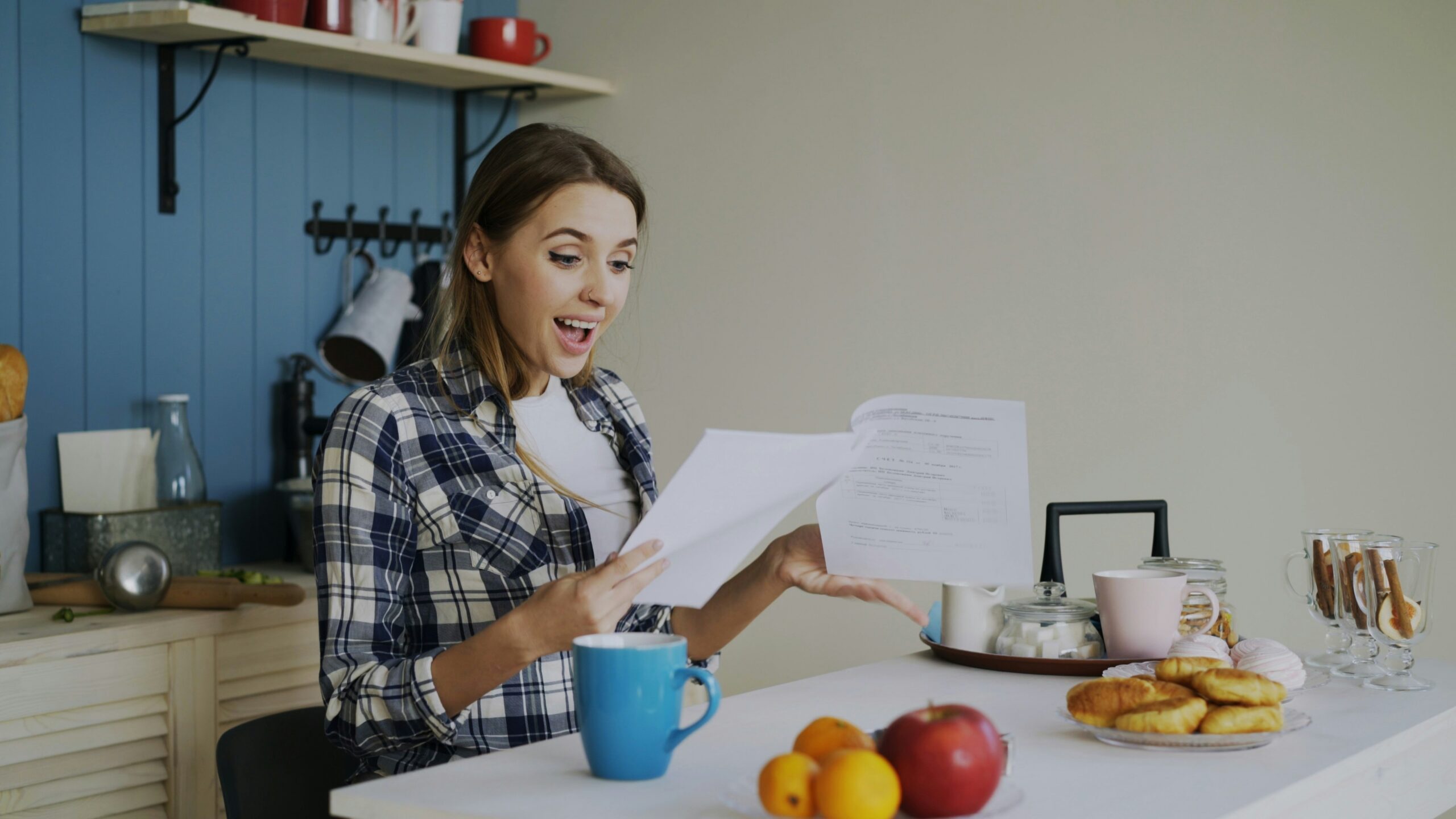 Woman with surprised expression reading documents at table