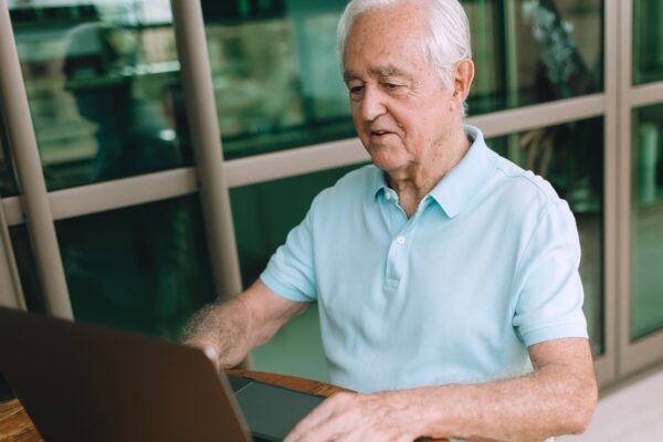 Elderly man enjoying technology, typing on laptop indoors.