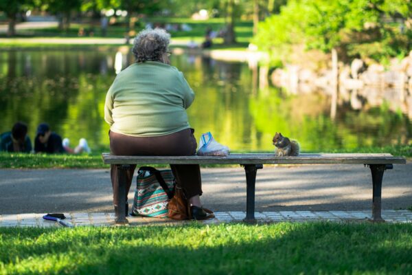 a woman sitting on a bench next to a cat