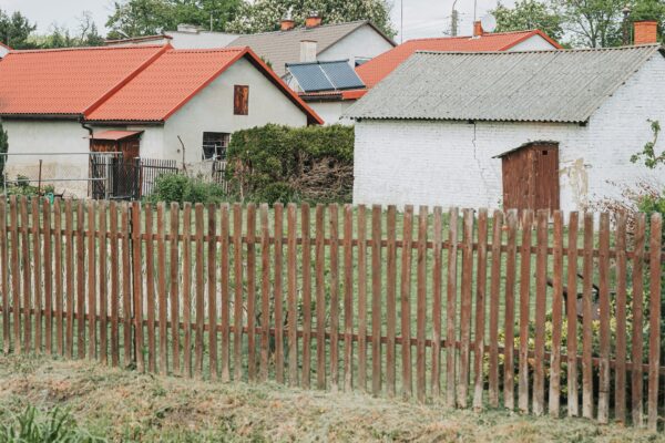 Village houses with red roofs behind a wooden fence