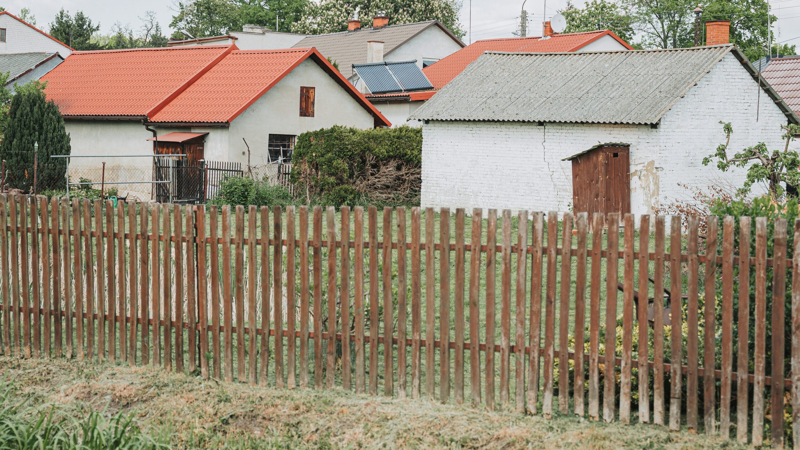 Village houses with red roofs behind a wooden fence