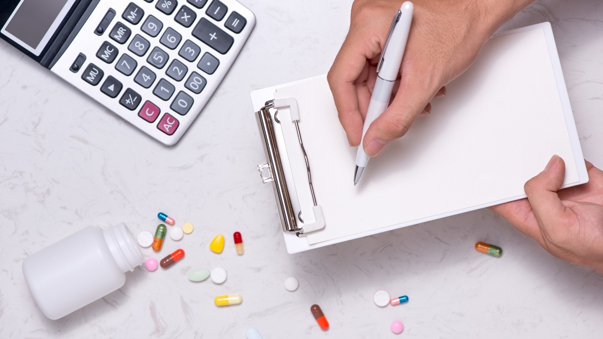 Healthcare costs concept. Opened medicine bottle and spilled out capsules on table.