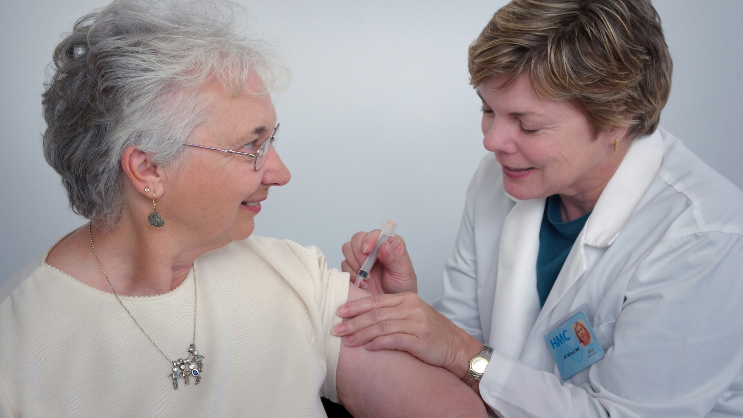 woman inject a woman on left shoulder