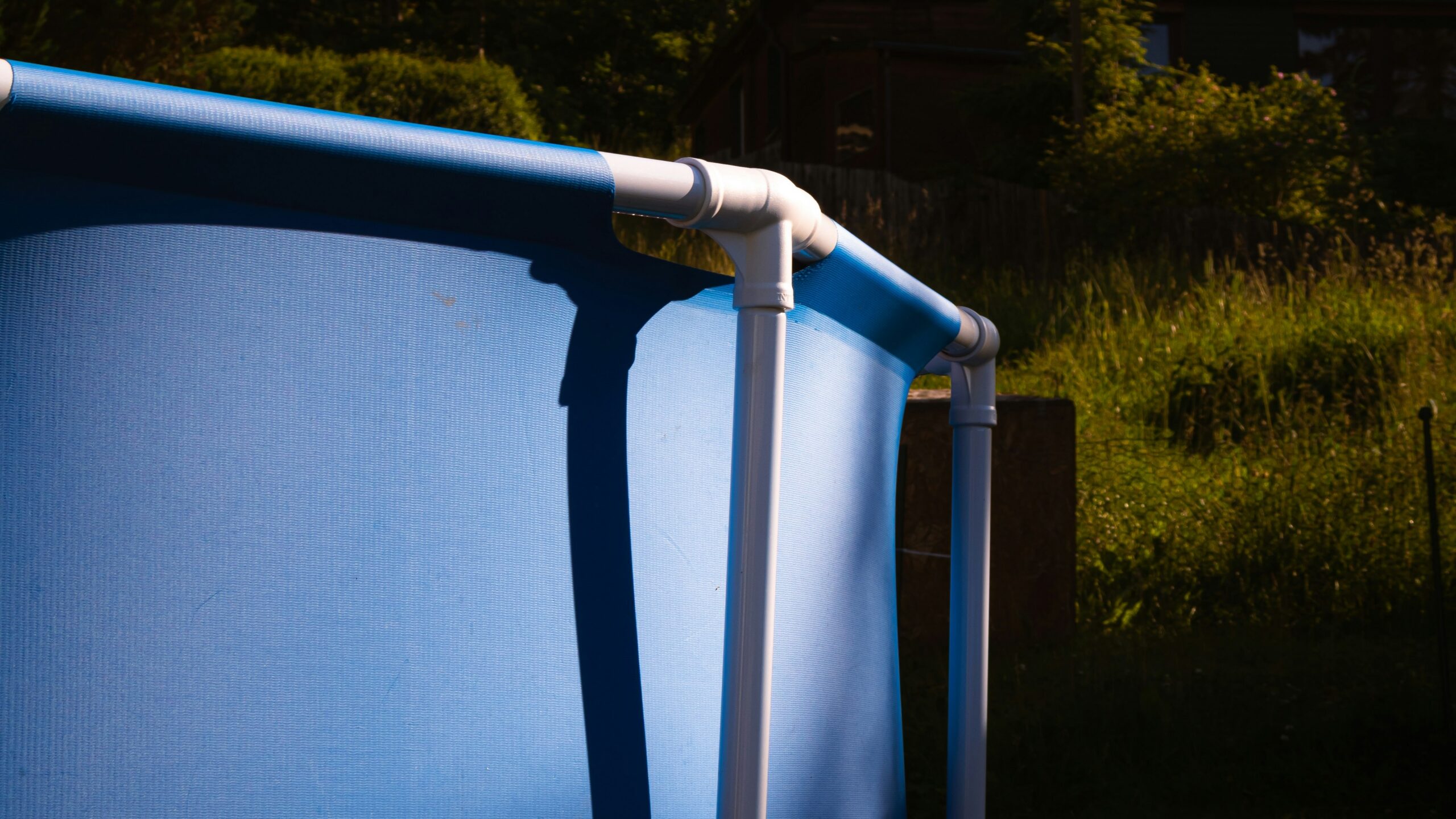 Blue above-ground pool with trees in the background