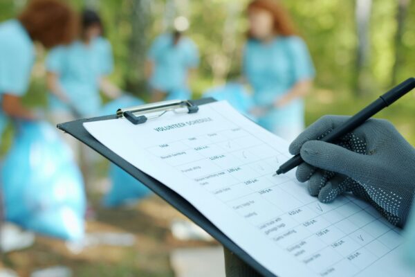 Person in gloves writing on clipboard during cleanup event