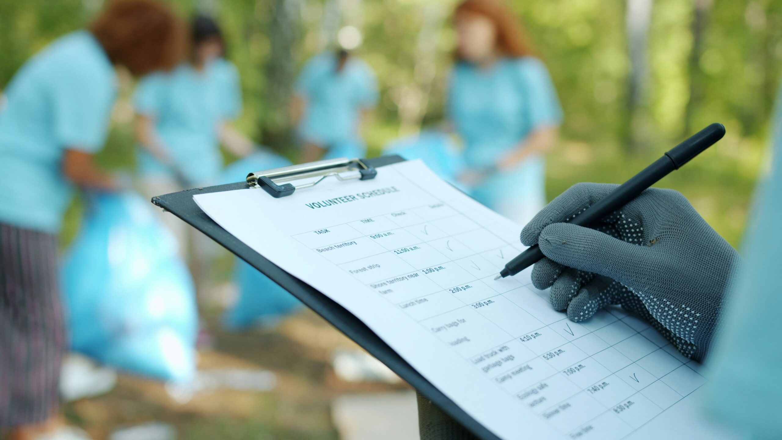 Person in gloves writing on clipboard during cleanup event