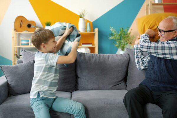 Boy and grandfather having a pillow fight on sofa