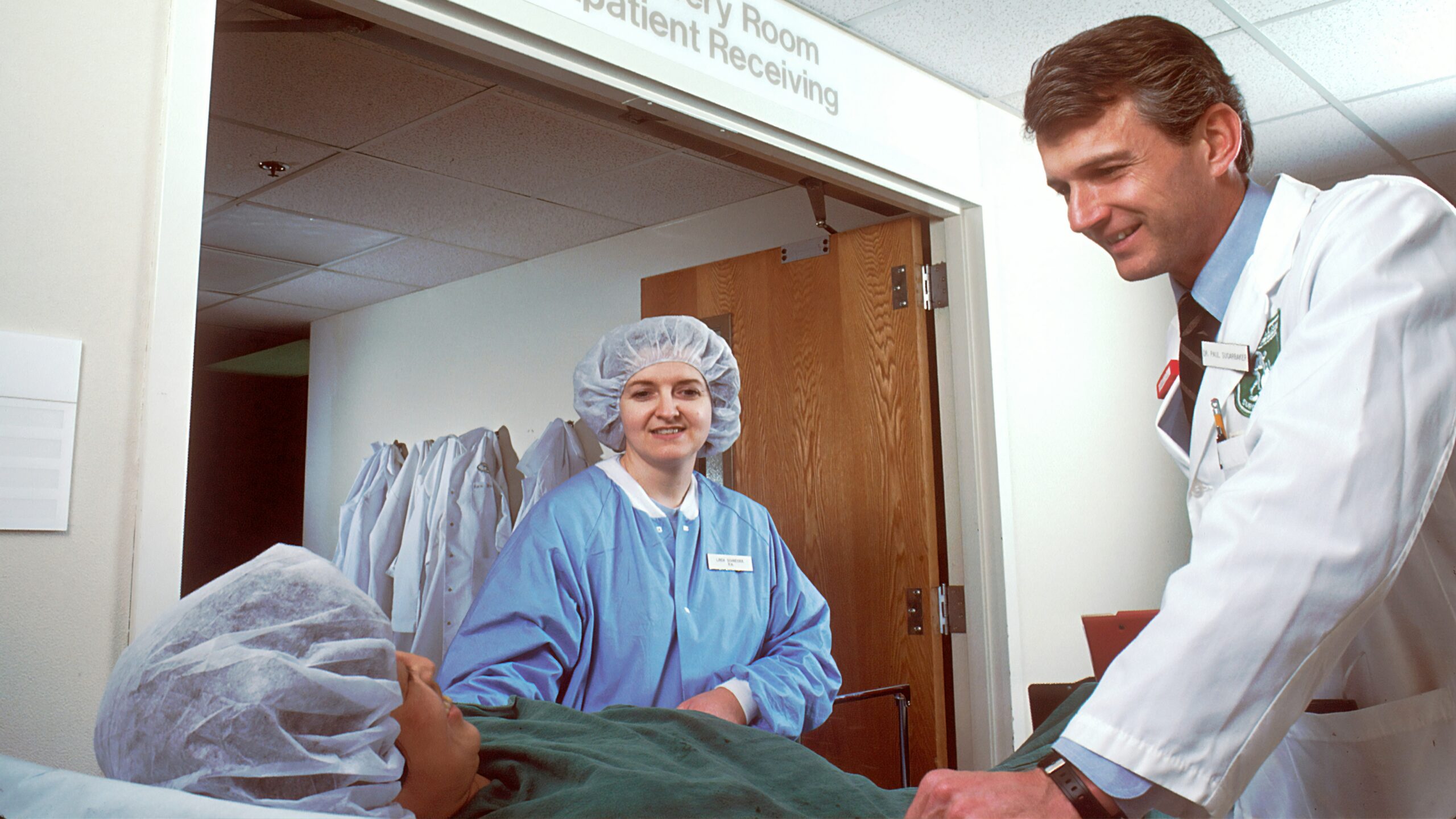 woman in blue scrub suit standing beside woman in white robe