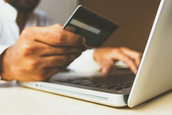person using laptop computer holding card