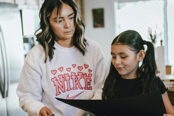 a woman standing next to a little girl in a kitchen