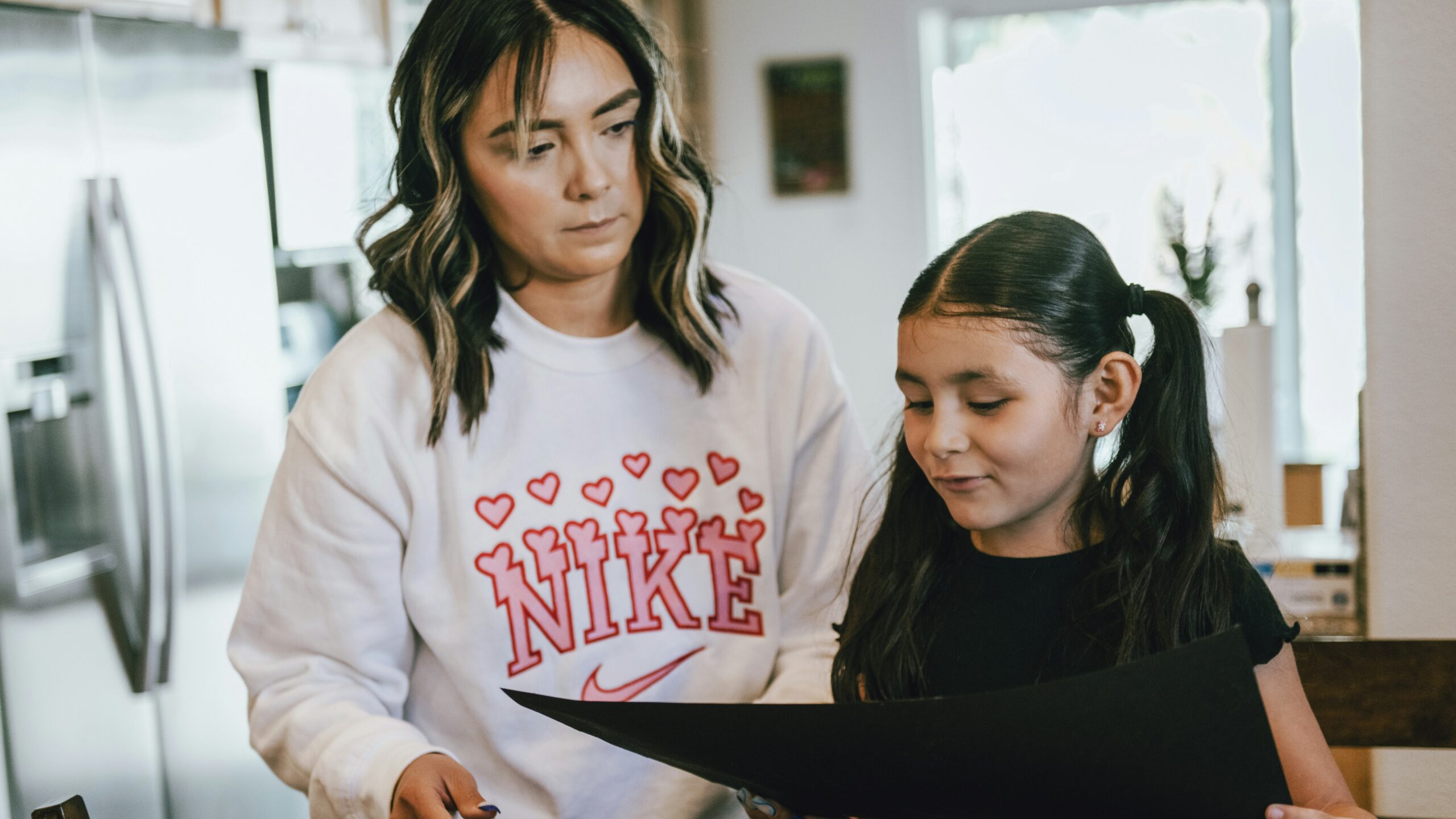 a woman standing next to a little girl in a kitchen