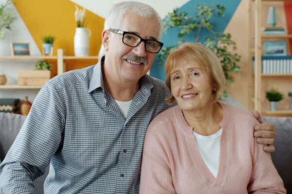 Elderly couple smiling together on a couch