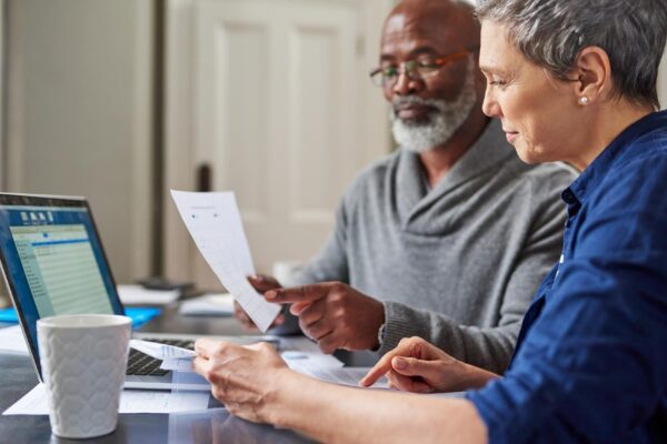 Laptop documents and finance with a senior couple busy on a budget review in the home together Accounting taxes or investment planning with a mature man and woman looking at insurance or savings