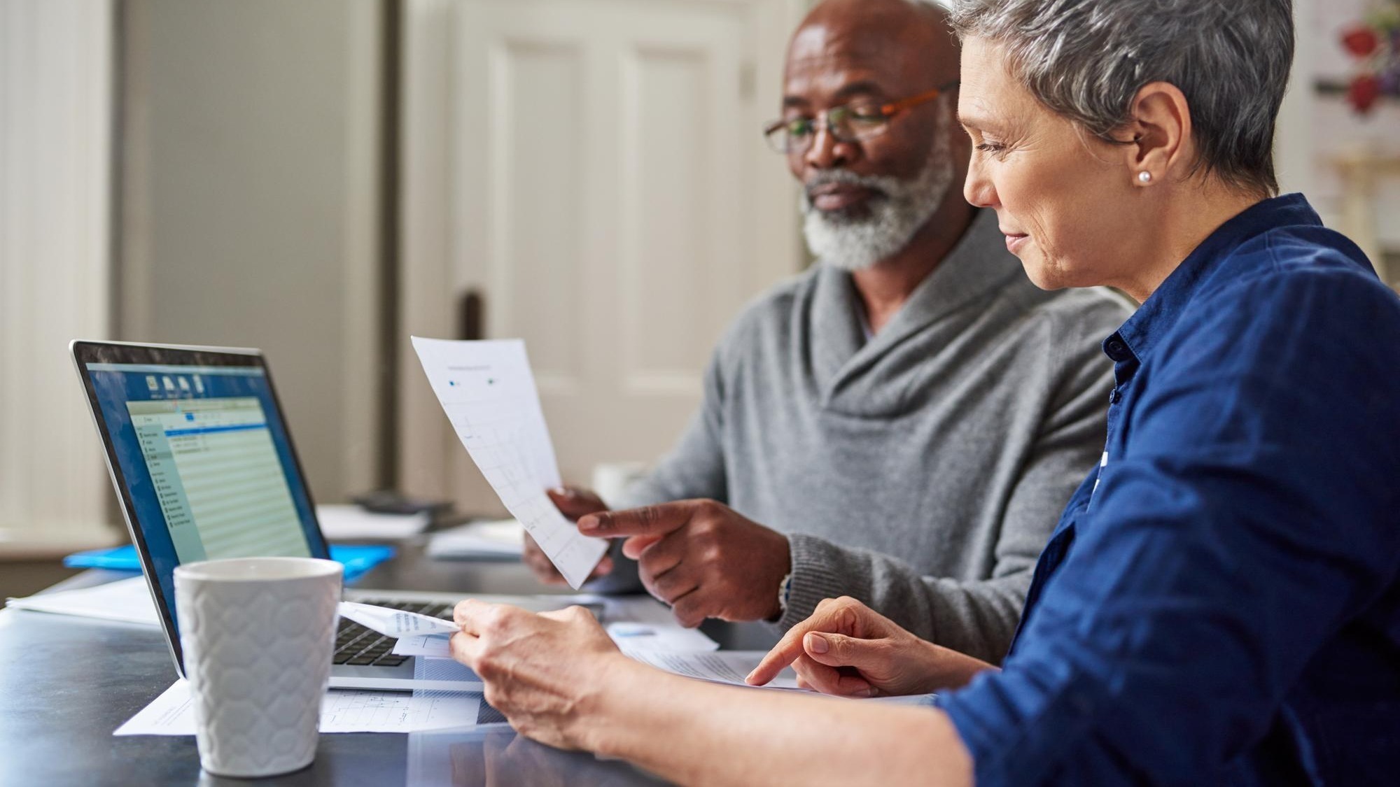 Laptop documents and finance with a senior couple busy on a budget review in the home together Accounting taxes or investment planning with a mature man and woman looking at insurance or savings
