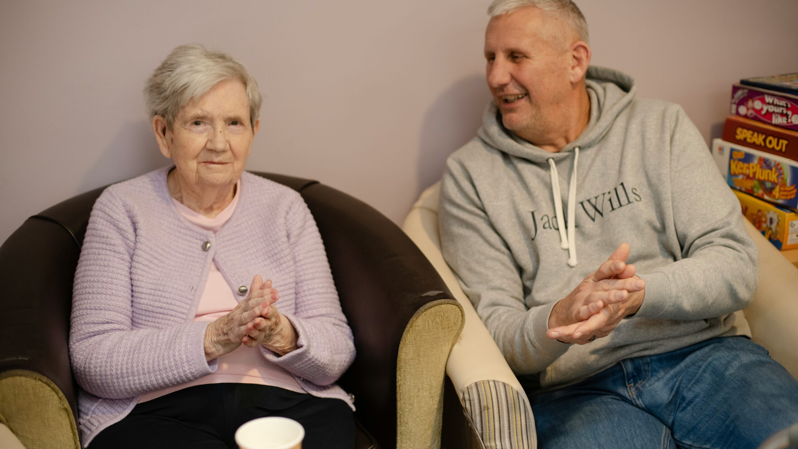 Elderly woman and man sitting in chairs clapping