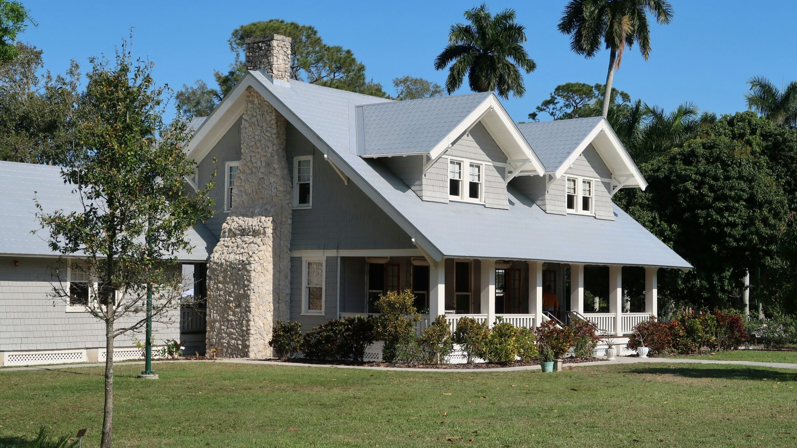 A grey house with a stone chimney and porch in Fort Myers, Florida