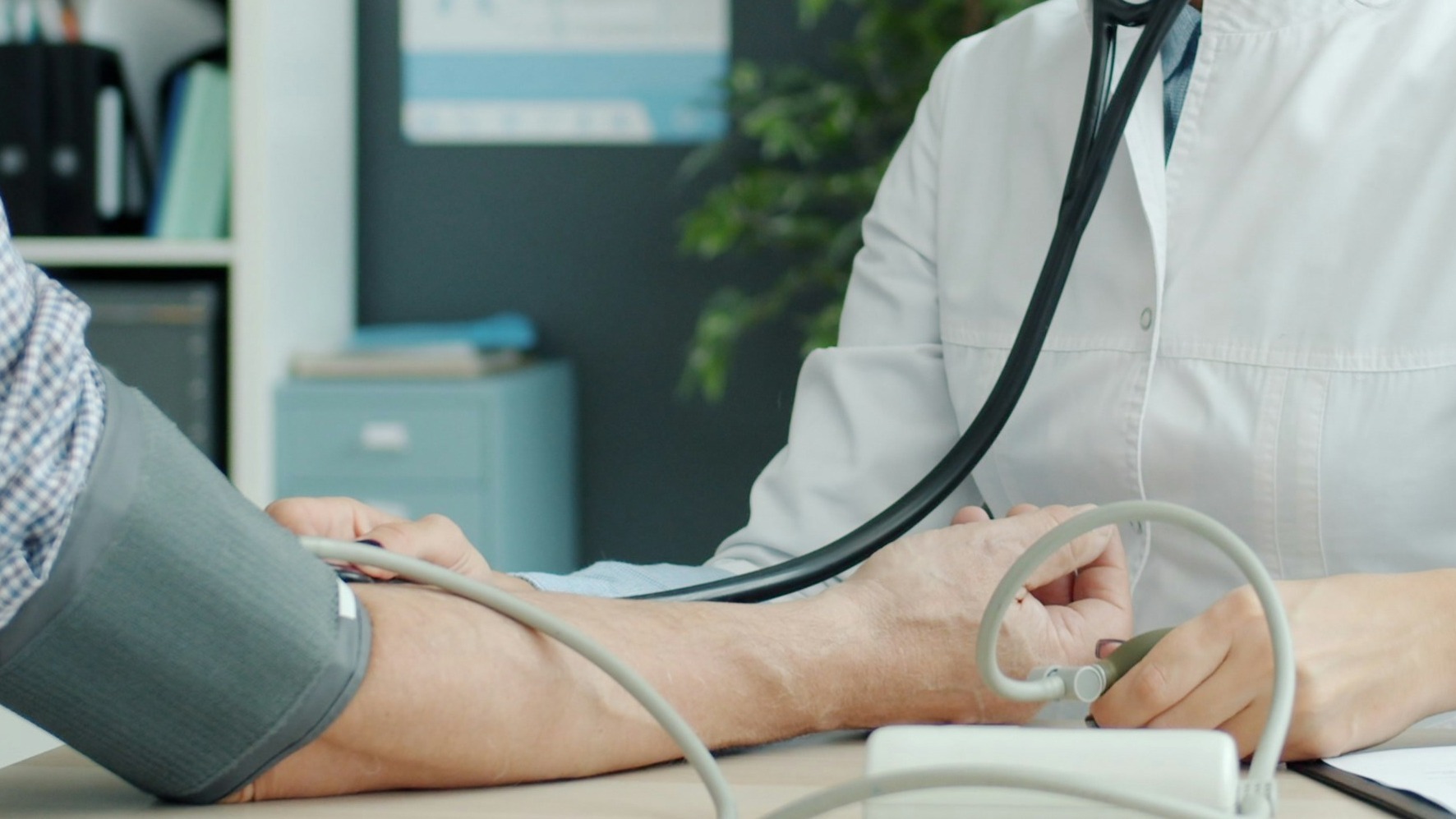 Doctor takes elderly patient's blood pressure.