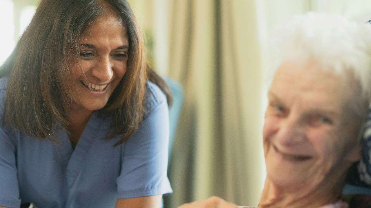 Nurse smiling with elderly patient in room