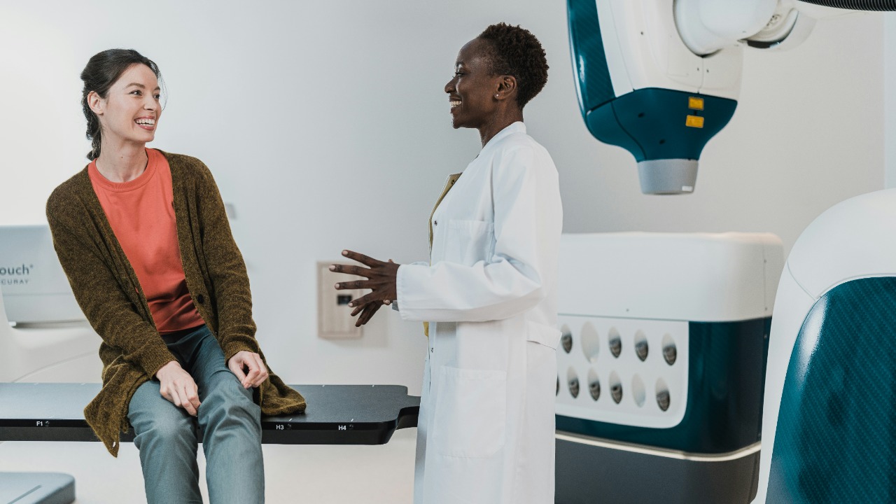 A doctor in a white coat talking to a patient in a medical room