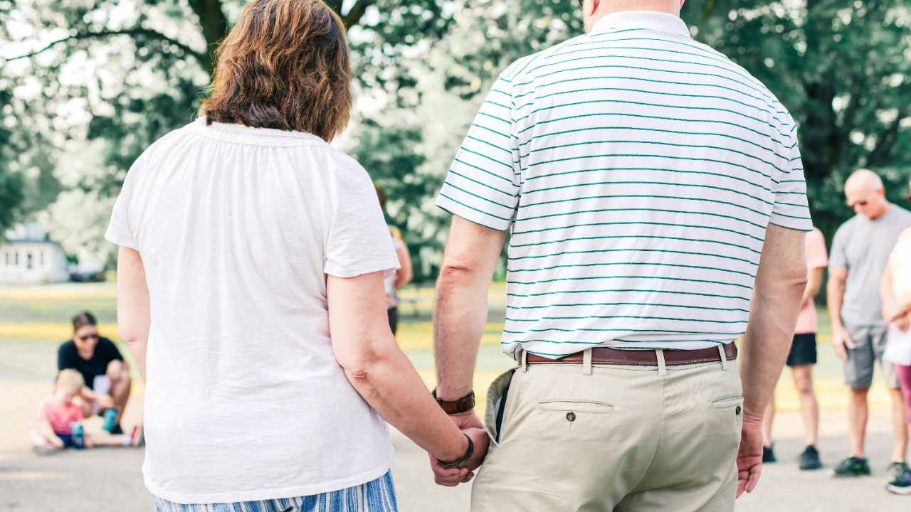 a man and a woman holding hands in a park