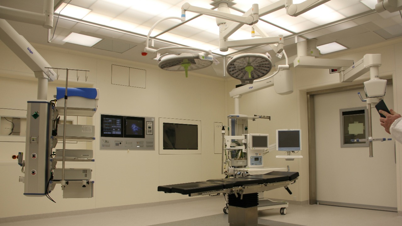 An operating room with a surgical table, overhead lights, and medical equipment