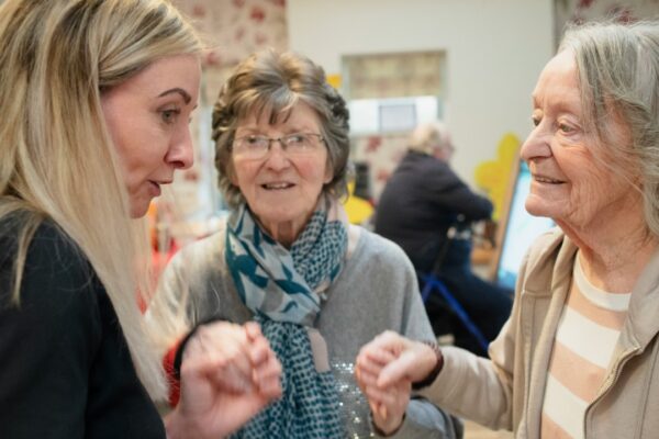 Three women interacting indoors with soft lighting
