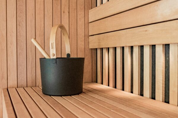 a wooden sauna with a black bucket and two wooden spoons