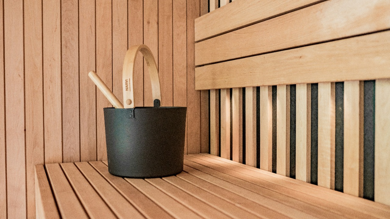 a wooden sauna with a black bucket and two wooden spoons