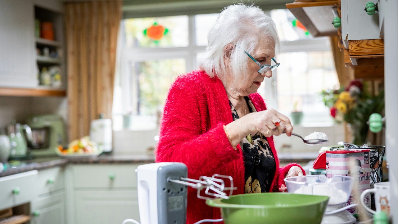 a woman in a red jacket is preparing food in a kitchen