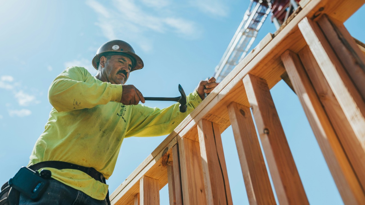 a man in a hard hat and safety gear working on a wooden structure