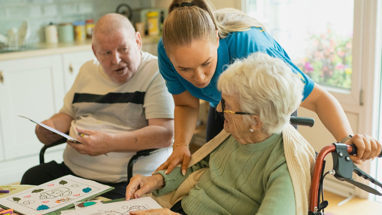 Caregiver assisting elderly couple with coloring
