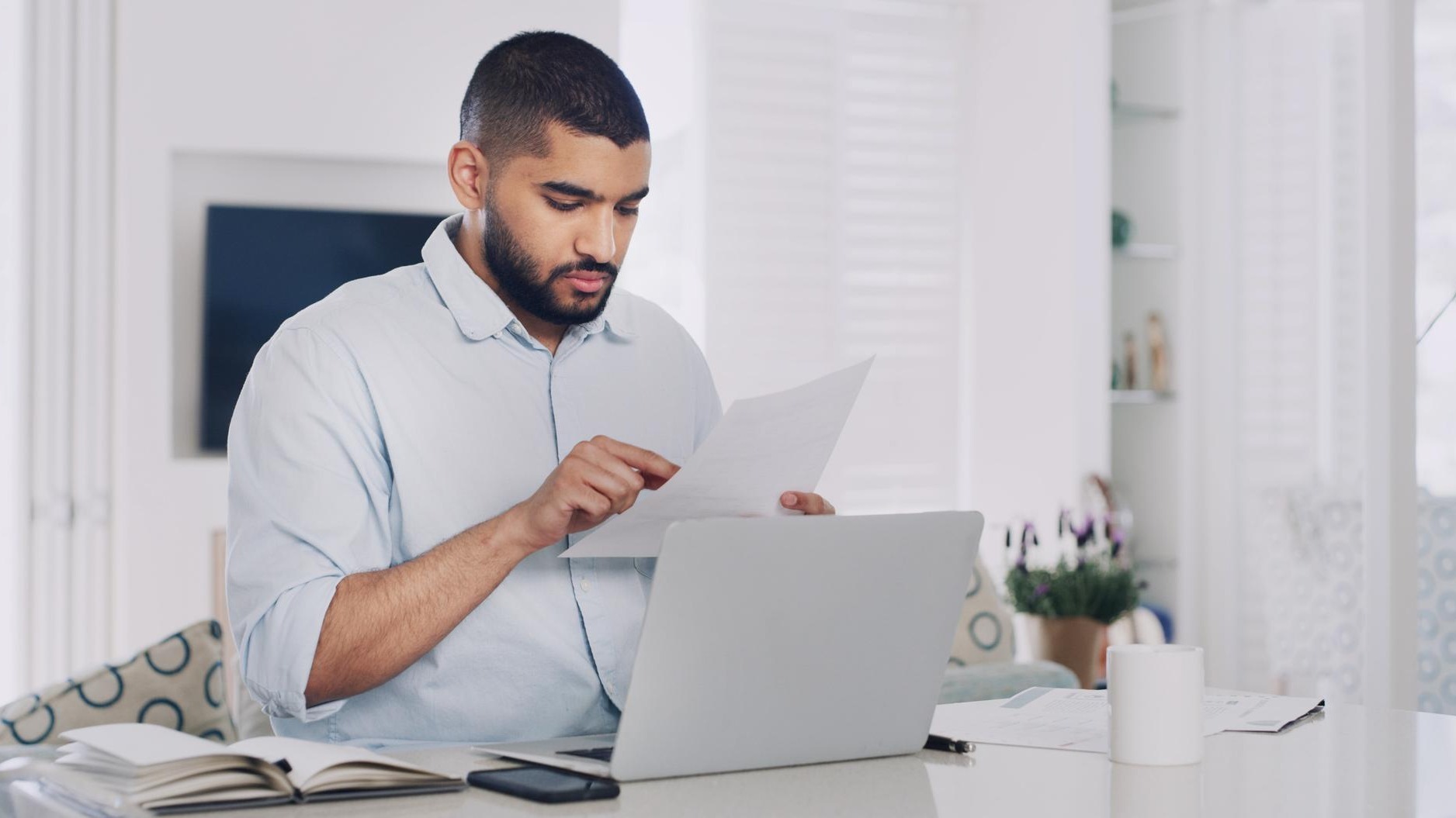 Remote work from home laptop and man with documents deadline and research for news report Person copywriting and journalist with PC editing and email for feedback reading and review for article
