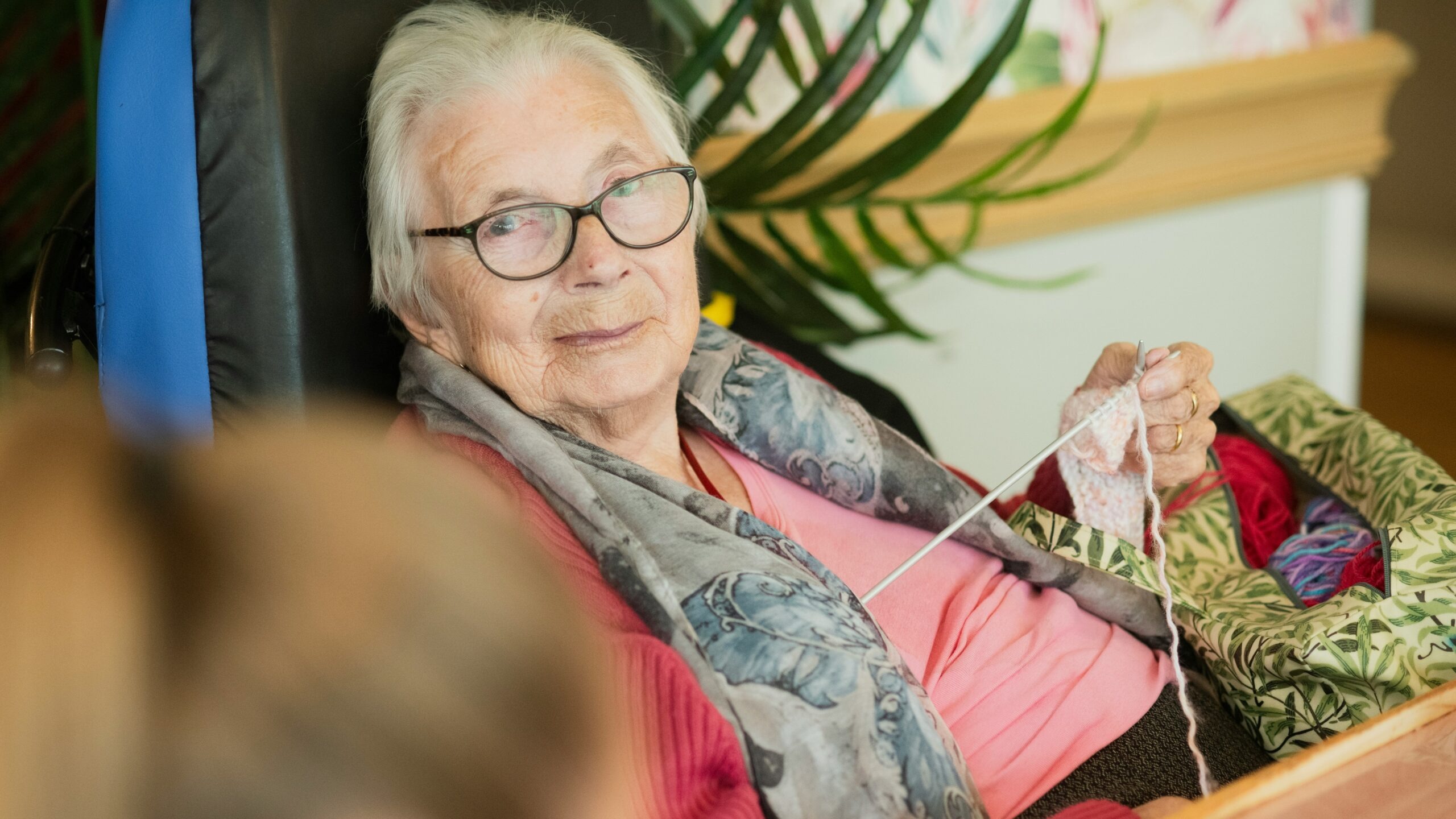 Elderly woman knitting in a wheelchair with a soft smile