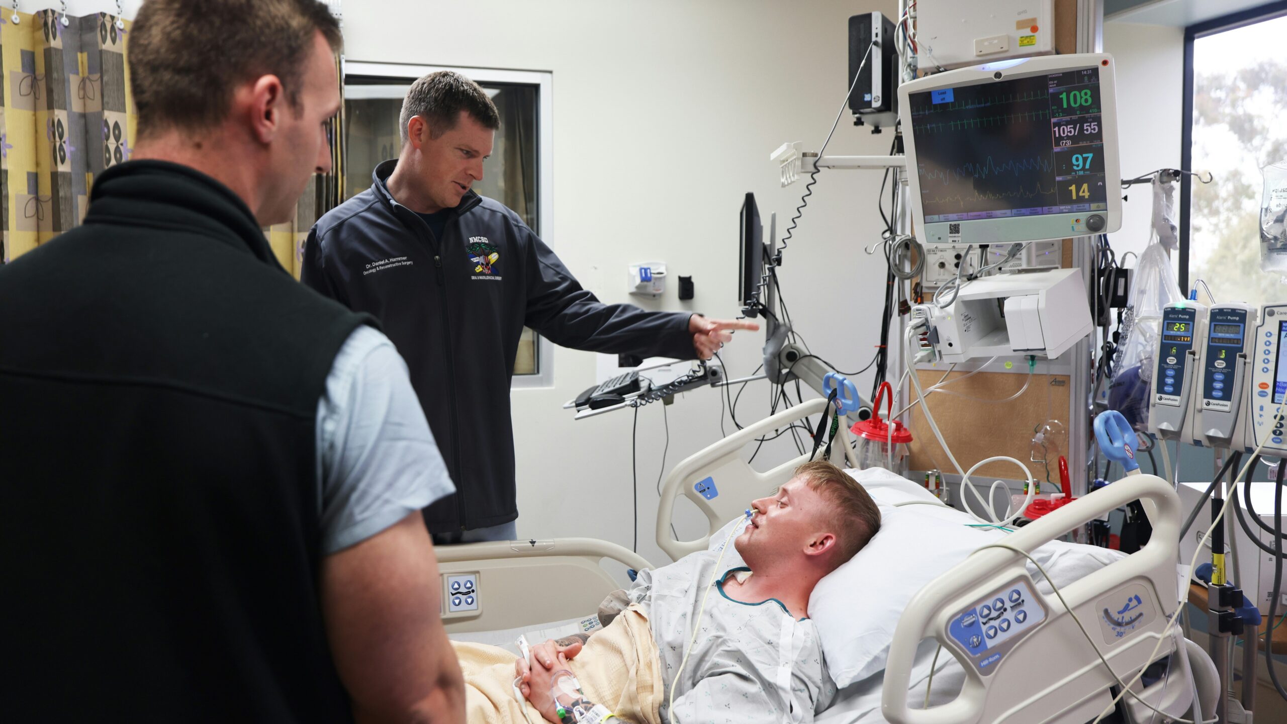 Doctors discuss patient's condition near hospital bed