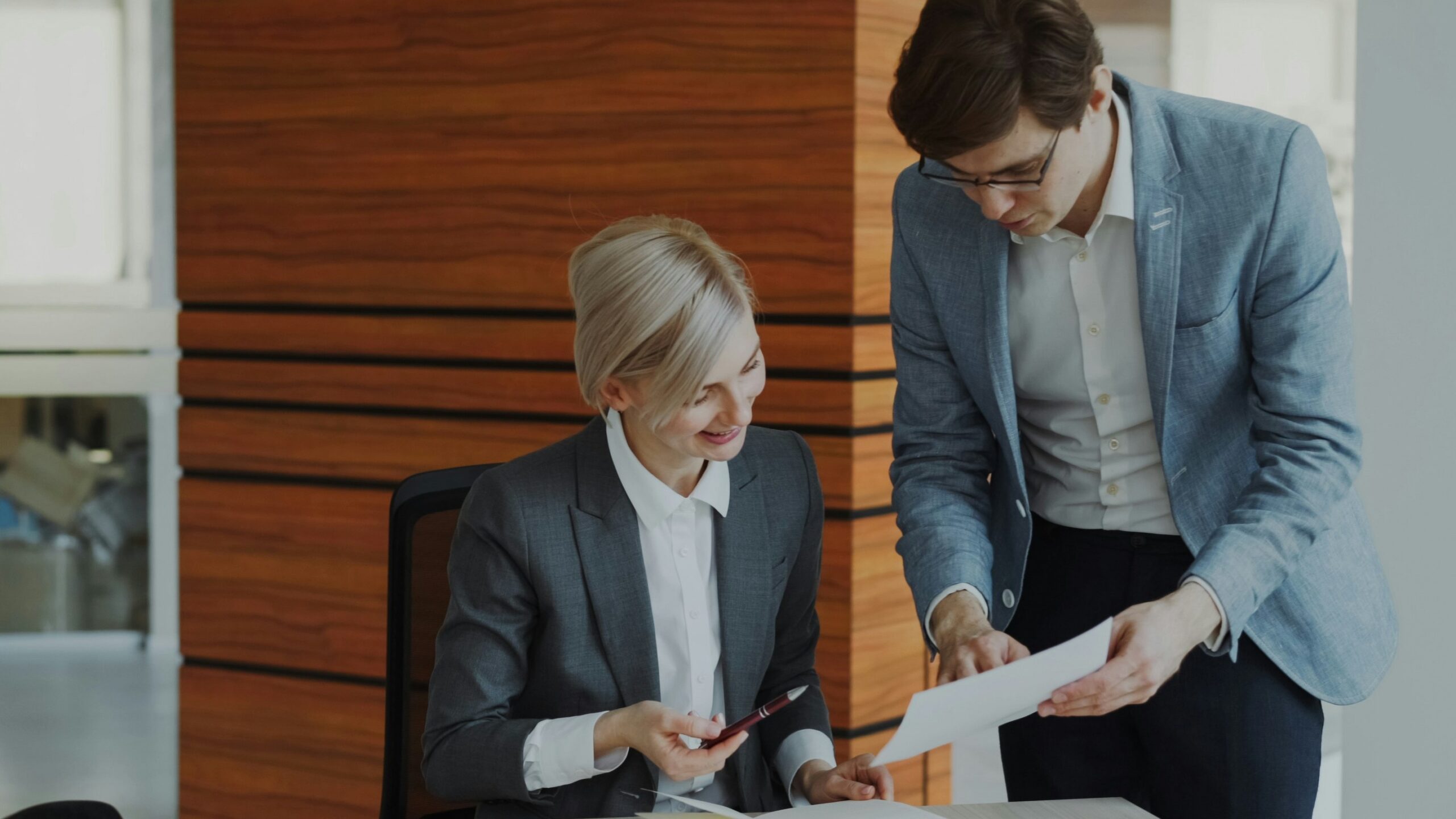 Two colleagues discussing documents at an office desk