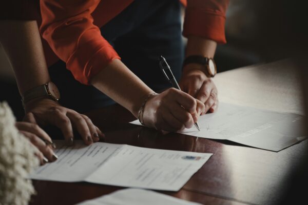 person in orange long sleeve shirt writing on white paper