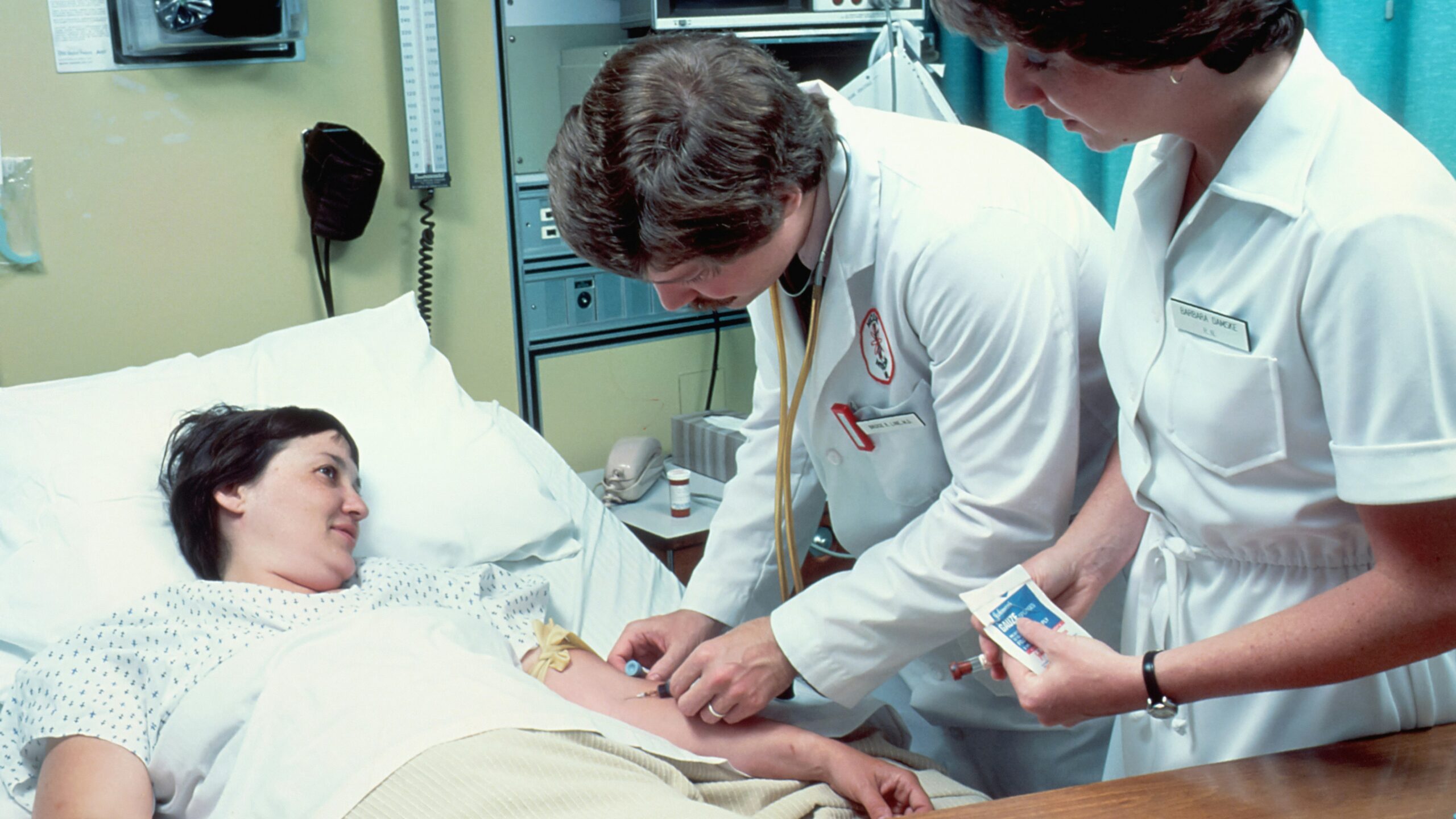 a woman laying in a hospital bed next to a man