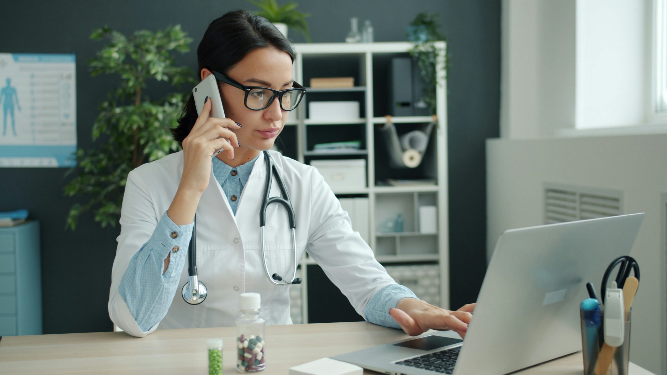 Doctor on phone, working on laptop in office