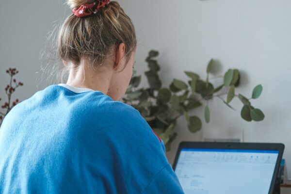 woman in blue sweater sitting in front of laptop computer