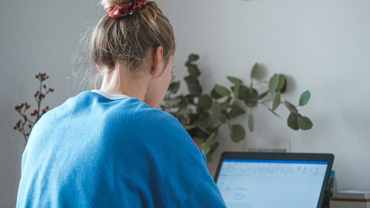 woman in blue sweater sitting in front of laptop computer