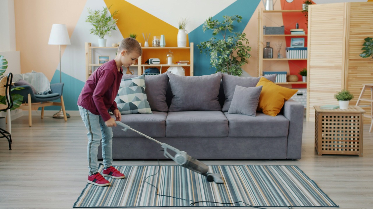 Young girl vacuuming a striped rug in a living room