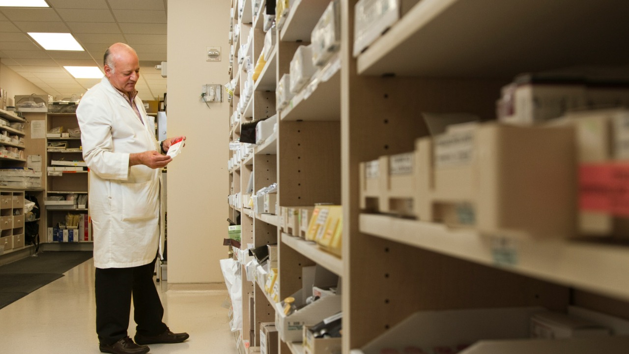 woman in white dress shirt and black pants standing near brown wooden shelf